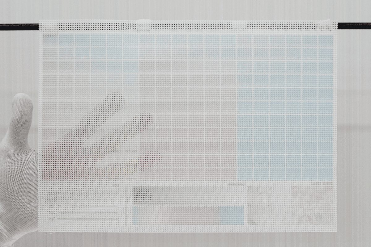 メッシュターポリンの生地サンプルに手をかざした写真